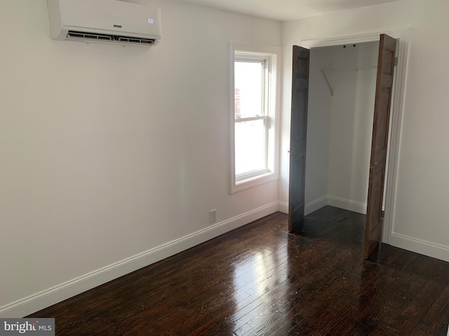 unfurnished bedroom featuring dark hardwood / wood-style floors and a wall mounted air conditioner