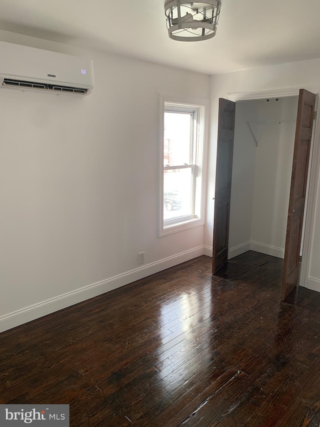 unfurnished bedroom featuring dark hardwood / wood-style flooring, a closet, and an AC wall unit