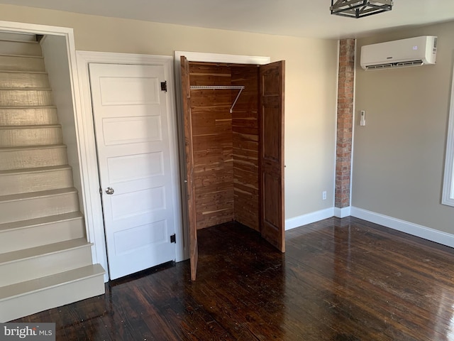 unfurnished bedroom with dark wood-type flooring and a wall unit AC