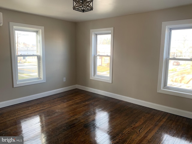 empty room with plenty of natural light, dark hardwood / wood-style floors, and a wall mounted AC