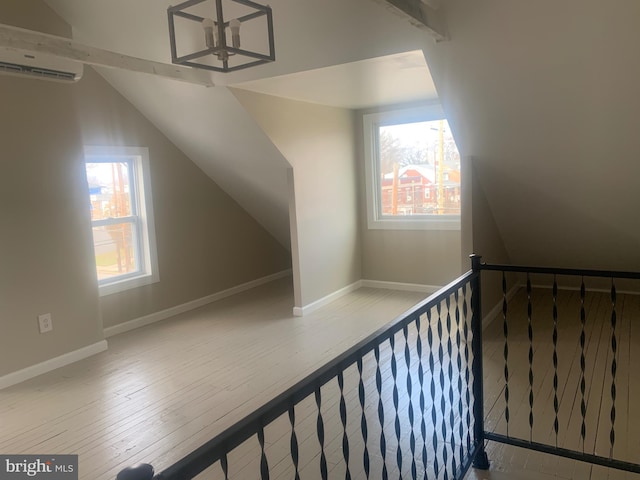 bonus room featuring vaulted ceiling, a wall mounted AC, and light hardwood / wood-style flooring