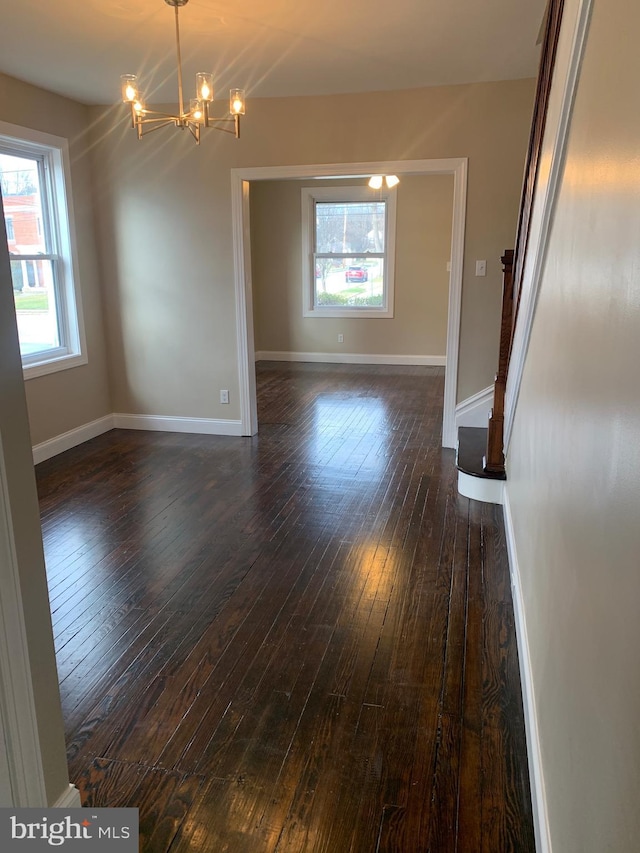 spare room with dark hardwood / wood-style floors and a chandelier