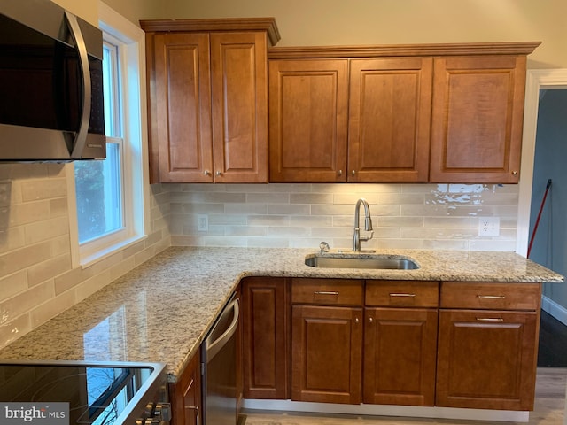 kitchen featuring light stone counters, appliances with stainless steel finishes, sink, and tasteful backsplash