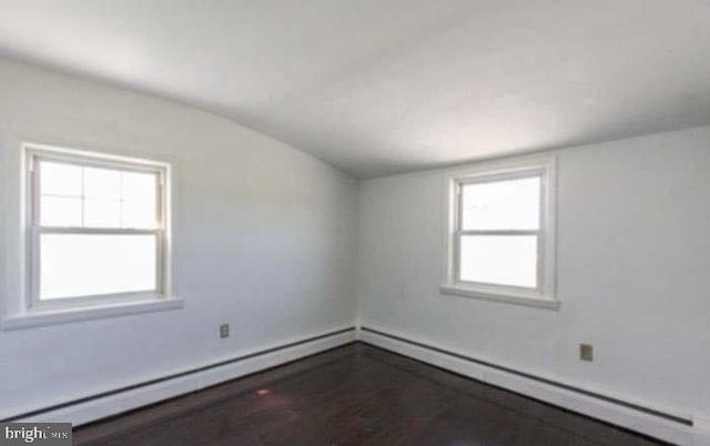 unfurnished room featuring baseboard heating, lofted ceiling, and hardwood / wood-style floors