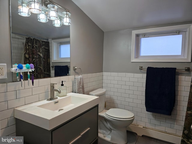 bathroom with a baseboard radiator, tile walls, vanity, and toilet