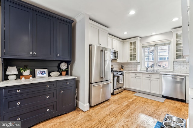 kitchen featuring stainless steel appliances, white cabinets, backsplash, and light hardwood / wood-style flooring