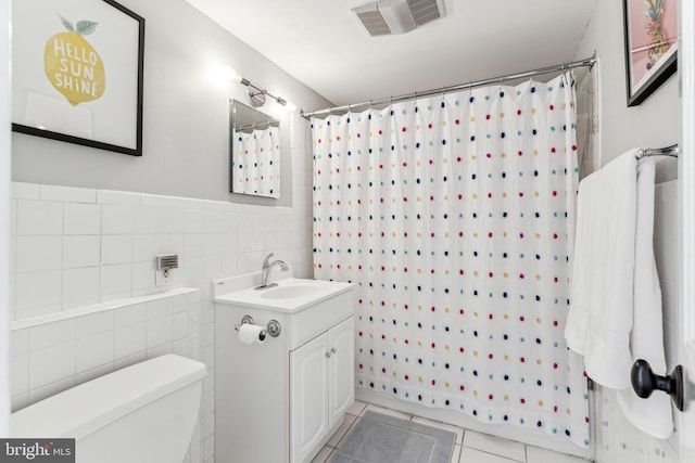 bathroom with tile patterned flooring, tile walls, vanity, curtained shower, and toilet