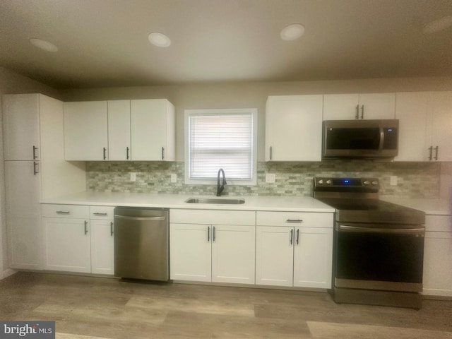 kitchen featuring stainless steel appliances, sink, decorative backsplash, and white cabinets