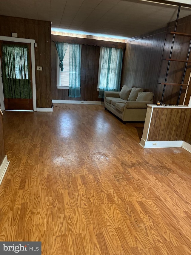 unfurnished living room featuring a wealth of natural light, wooden walls, and light hardwood / wood-style flooring