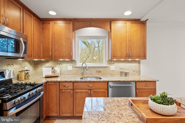 kitchen featuring light stone counters, sink, backsplash, and stainless steel appliances