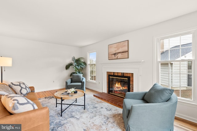 living room featuring a brick fireplace and light hardwood / wood-style flooring