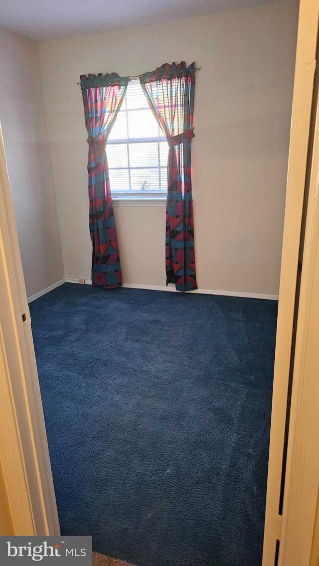 spare room featuring carpet floors and baseboards