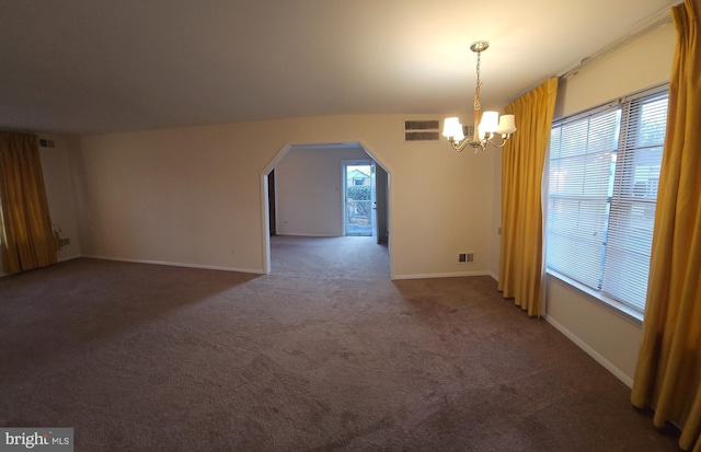 unfurnished dining area with arched walkways, carpet floors, visible vents, and a notable chandelier