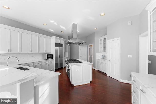 kitchen featuring light stone counters, dark wood-style floors, stainless steel built in fridge, a sink, and exhaust hood