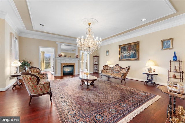 living room with ornamental molding, a glass covered fireplace, baseboards, and wood finished floors