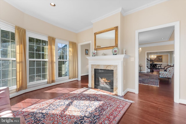 living area featuring a notable chandelier, crown molding, a high end fireplace, wood finished floors, and baseboards