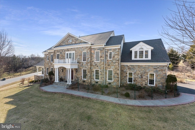 view of front of house featuring a balcony and a front lawn