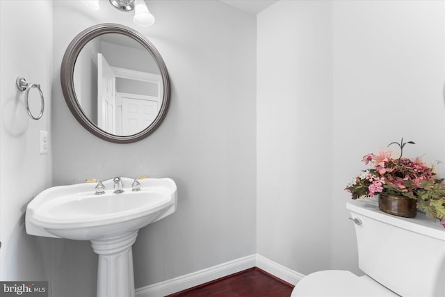 half bath featuring toilet, baseboards, and wood finished floors