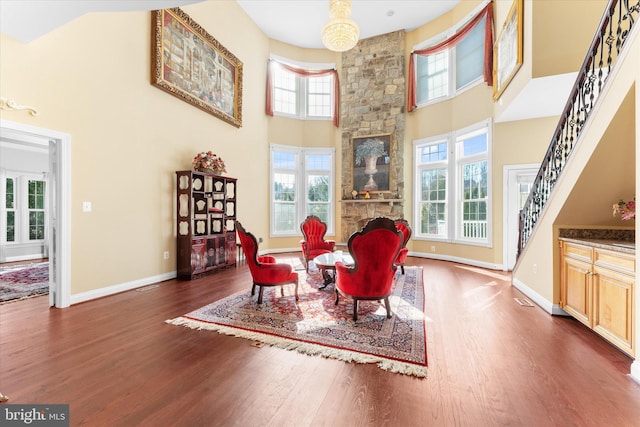 sitting room featuring a towering ceiling, baseboards, stairway, and wood finished floors