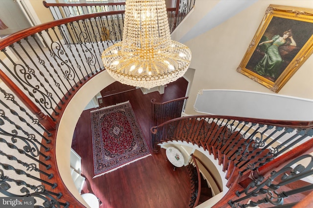 stairs featuring wood finished floors and a notable chandelier