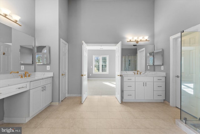 bathroom featuring a towering ceiling, a shower stall, and a sink