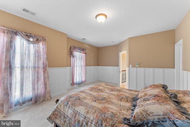 bedroom featuring a wainscoted wall, carpet floors, and visible vents