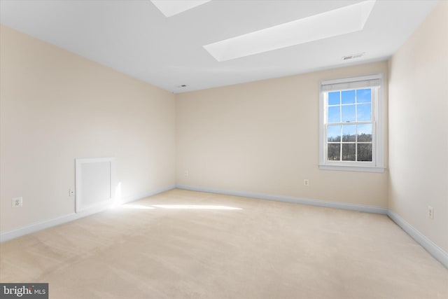 unfurnished room with baseboards, a skylight, visible vents, and light colored carpet