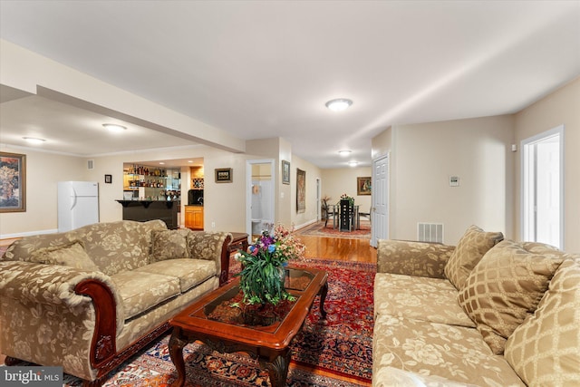 living area featuring indoor bar, wood finished floors, and visible vents