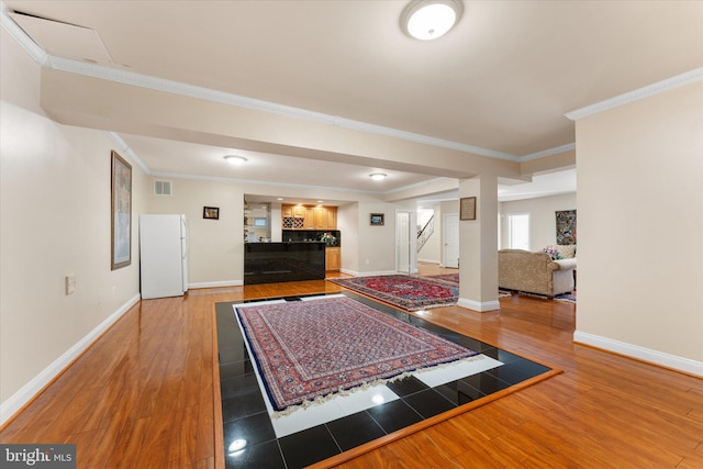 entrance foyer with baseboards, visible vents, wood finished floors, and ornamental molding