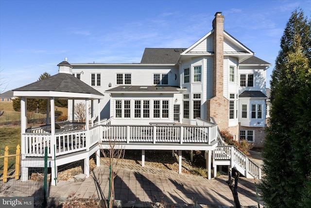 back of house with a chimney, stairs, a deck, a gazebo, and a patio area