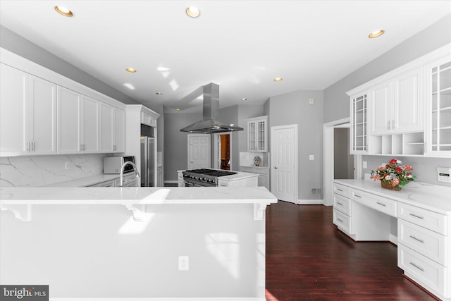 kitchen with dark wood-style floors, high end appliances, tasteful backsplash, island range hood, and a peninsula