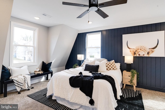 carpeted bedroom with wooden walls and ceiling fan