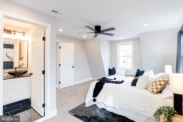 carpeted bedroom with ceiling fan and sink