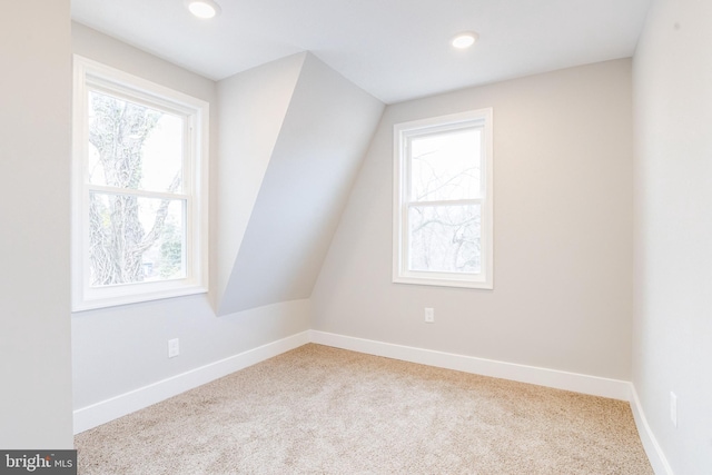 bonus room with light colored carpet, a healthy amount of sunlight, and lofted ceiling