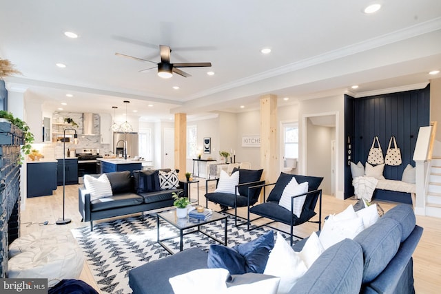 living room featuring crown molding, a fireplace, ceiling fan, and light wood-type flooring