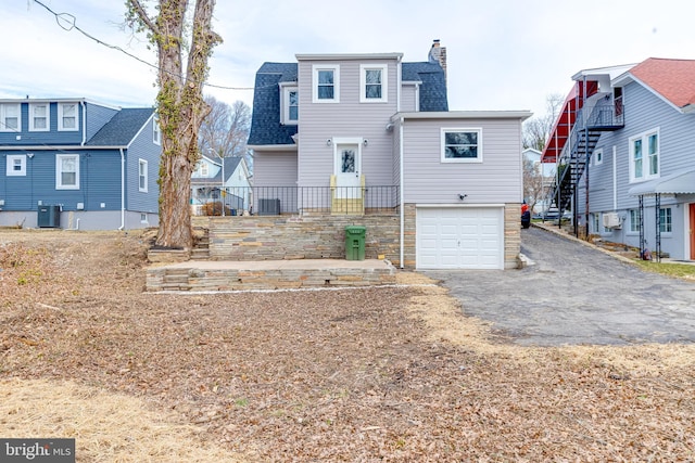 rear view of house with a garage and central AC