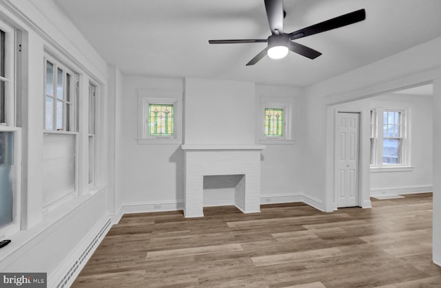 unfurnished living room featuring a brick fireplace, plenty of natural light, and light wood-type flooring