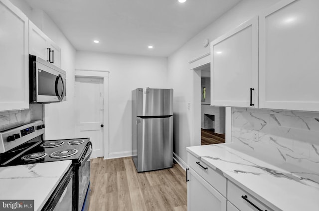 kitchen featuring stainless steel appliances, backsplash, white cabinets, and light stone counters