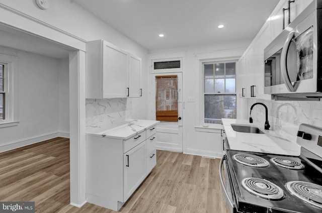 kitchen featuring white cabinetry, stainless steel appliances, light stone countertops, and sink