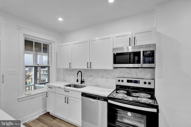 kitchen featuring stainless steel appliances, white cabinetry, sink, and backsplash