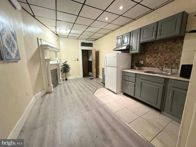 kitchen featuring white refrigerator, gray cabinets, sink, and backsplash