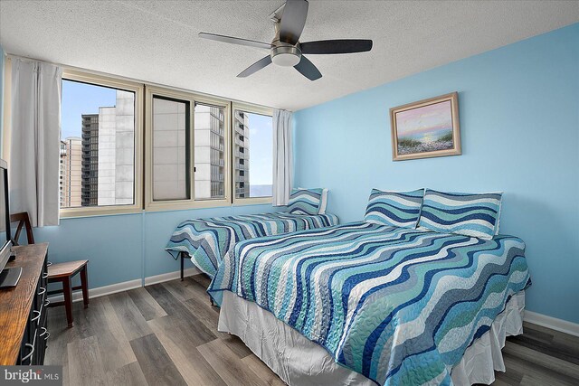 bedroom with ceiling fan, a textured ceiling, and dark hardwood / wood-style flooring