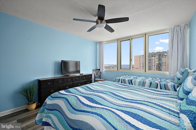 bedroom with ceiling fan, dark hardwood / wood-style floors, and a textured ceiling