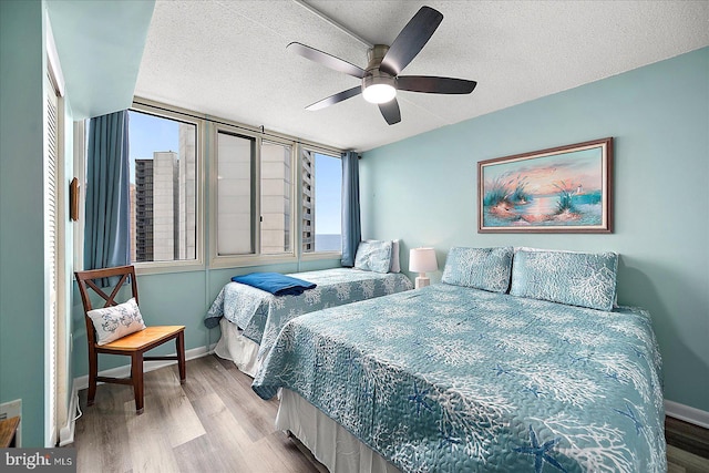 bedroom featuring ceiling fan, light hardwood / wood-style flooring, and a textured ceiling