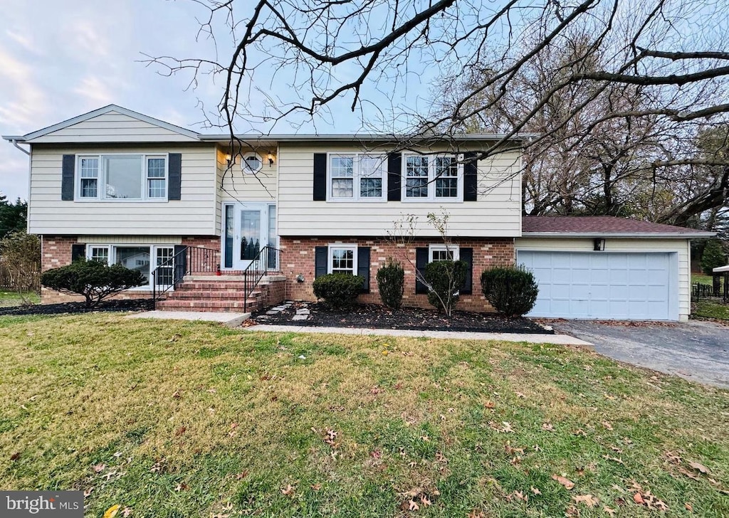 bi-level home featuring a garage and a front lawn