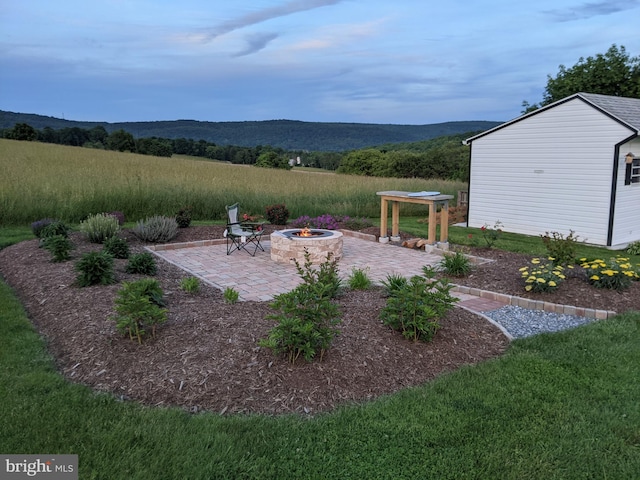 view of yard featuring a patio, a mountain view, an outbuilding, and an outdoor fire pit