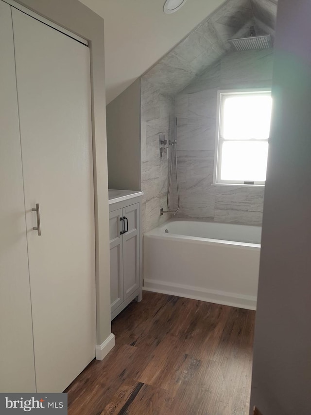 bathroom with hardwood / wood-style flooring, vanity, and tiled shower / bath