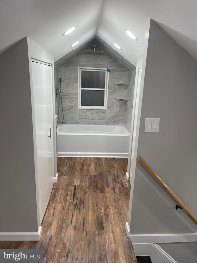 bathroom with lofted ceiling, hardwood / wood-style floors, and tiled shower / bath combo