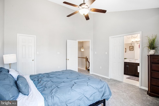 bedroom featuring ceiling fan, ensuite bathroom, high vaulted ceiling, and light carpet