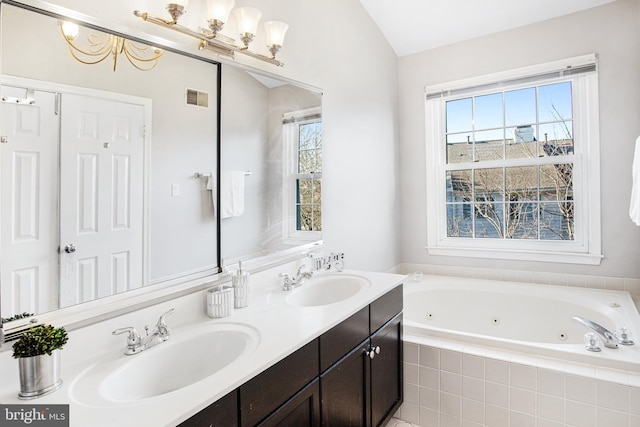 bathroom featuring vanity, tiled tub, and vaulted ceiling